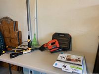 Tools and garden equipment on table including Black and Decker skill saw and TV mount box