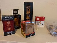 Overview photo showing six puzzle boxes unopened in original packaging, with various designs and boxes of different sizes, plus the cork tray trivet wrapped separately.