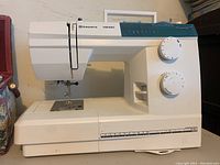 Full side view of the Husqvarna Viking Emerald 116 sewing machine showing body, dials, and base with measurement markings.