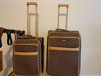 Two brown Pierre Cardin rolling suitcases with tan trim, standing upright with extended handles.