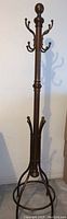Photo of rubbed bronze antique metal coat rack with multiple double hooks arranged vertically for hanging.