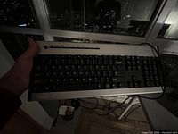 Full view of the wired keyboard held in hand showing layout and cable