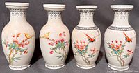 Front view of four porcelain vases showing hand-painted birds and blossoms
