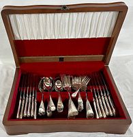 Open view of the wooden box showing all flatware pieces organized in slots
