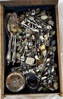 Full view of antique silverplated spoons, serving spoons, and small dishes inside a wooden drawer with lined interior