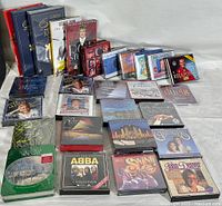 Overview of a large assortment of music CDs in jewel cases and boxed sets arranged on a white surface, showing the variety of artists and styles.
