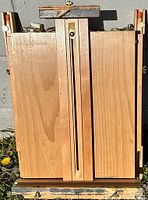 Front view of folded portable art easel showing beechwood panels with vertical slots and brass clamp.