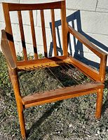 Front perspective of teak lounge chair showing slatted back and sinuous spring seat support