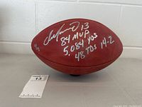 Full view of brown leather football with silver autograph and inscriptions
