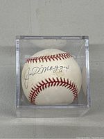 Autographed baseball centered in clear acrylic case on gray surface
