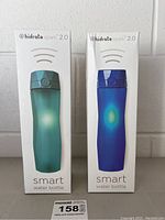 Two boxed Hidrate Spark 2.0 smart water bottles in teal and blue colors shown front facing