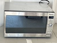 Front and angled views of Panasonic NN-SD670S stainless steel microwave showing control panel and door with black tinted glass.