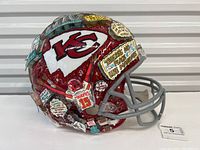 Oblique side view of decorated football helmet showing Kansas City Chiefs logo, Patrick Mahomes illustration and collage elements.