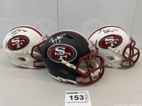 Overview of three SF 49ers mini helmets (two white, one black) with red facemasks and logos
