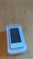 Top view of the pink iPod Nano inside transparent plastic case showing screen and home button.