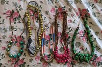 Photo showing six beaded necklaces on floral fabric background with varied colors and bead styles