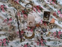 Photo showing a spread of various costume jewelry pieces including necklaces, bracelets, brooches, and earrings laid out on a floral fabric.