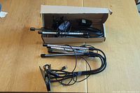 Two sets of LED plant growing lights shown with flexible gooseneck arms and clamp bases. One set partially inside a box with accompanying power adapter.