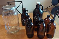 Photo showing all items: large clear Mason jar, six amber jars, two black Collective Arts growlers