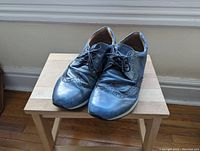 Front and top angle view showing worn blue leather Geox men's shoes with brogue perforations and lace closure.