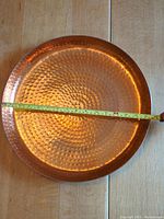 Top view of a large hammered copper metal tray with visible diameter measurement showing about 21 inches across.