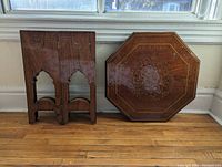 Photo of table top and folded legs side by side showing intricate octagonal inlay top and carved foldable legs.