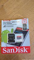 Photo of sealed SanDisk Ultra 64GB microSDXC UHS-I card retail packaging including card and adapter