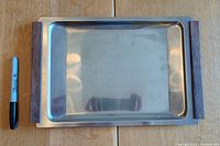 Top view of rectangular stainless steel serving tray with wood handles on each end; Sharpie pen placed beside tray for size reference.