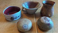 Five studio pottery pieces arranged on wooden surface