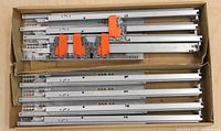 Box with metal drawer slides and orange locking devices inside.