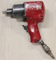 Side view of red Chicago Pneumatic air impact wrench with 1/2 inch drive, showing trigger and air inlet hose fitting.