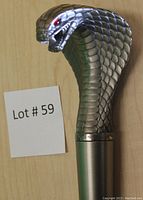 Close-up of silver-tone cobra head handle with scale texture and red eyes
