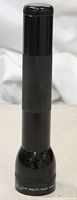 Full frontal view of black Mag-Lite flashlight showing cylindrical shape and textured grip area.