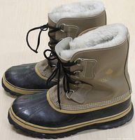 Side perspective of the men's winter boots showing lace-up front, white fleece lining, and tan leather upper with black rubber lower and sole.