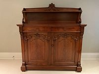 Front view of entire chiffonier sideboard showing carved trim, paneled doors and upper shelf