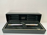 Cross ballpoint pen with gold and silver metal finishes in original black box with gold trim, showing inside of box with pen secured by black strap, Cross logo and text inside box lid.