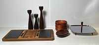 Full lot view including wooden charcuterie board with slate inserts and knives, stacked and oval wooden bowls, chrome serving tray with Bakelite legs, and three wooden candle holders.