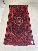 Full view of the Persian carpet runner laid on a light carpeted floor showing the entire rectangular shape and pattern.