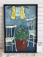 Framed oil painting depicting two white chairs and a red pot of pink tulips against a blue interior wall with a small window and yellow curtains. MaxSold sticker visible in corner.