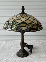 Photo showing the Tiffany style stained glass lamp fully assembled including metal base and finial, with visible multi-colored glass pattern and power cord.