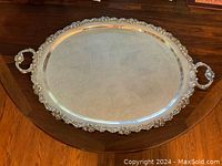 Full top view of the large oval silver plate footed tray with floral etched pattern and ornate handles.