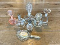 Seven vintage perfume bottles displayed on wooden surface, showing varied styles and stoppers.