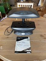 Front view of AeroGarden VeggiePRO on wood table with instruction booklet placed in front.