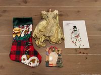 Photo of all included Christmas decorations: stocking, angel tree topper, picture frame, and snowman window hanging on wooden floor