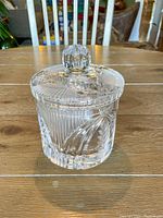 Front view of the cut crystal jar with lid on wooden table showing detailed cut patterns and knob handle on lid.