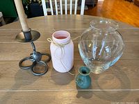 Lot showing all four items: clear glass vase, pink painted Mason jar, blue-green bud vase with frog, wrought iron candleholder with beeswax taper