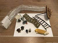 Overview of all miniature garden items including fences, bird bath, ladder, path, umbrella, and animal figures spread on a flat surface.