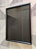 Front view of large black shadow box frame, showing glass front and black frame