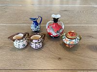 Front view of the five miniature ceramic decorative items arranged on a wooden floor.