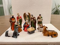 Full set of 11 nativity figures arranged on a wooden table against a white background, showing all figures together.